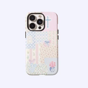 Op de afbeelding: Decoratieve telefoonhoes met een patchwork-ontwerp. Het heeft bloemen-, streep- en ruitpatronen in pastelroze, blauw en wit. De hoes bevat een kruis, een strik en een vaas met bloemen.