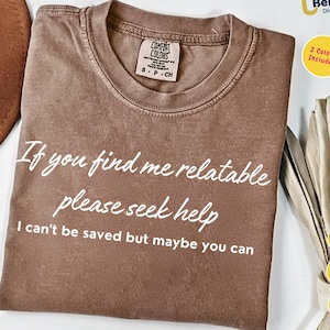 May include: A brown Comfort Colors t-shirt with the text "If you find me relatable please seek help I can't be saved but maybe you can" in white. The shirt is a size small/petite/child. A brown hat is partially visible.