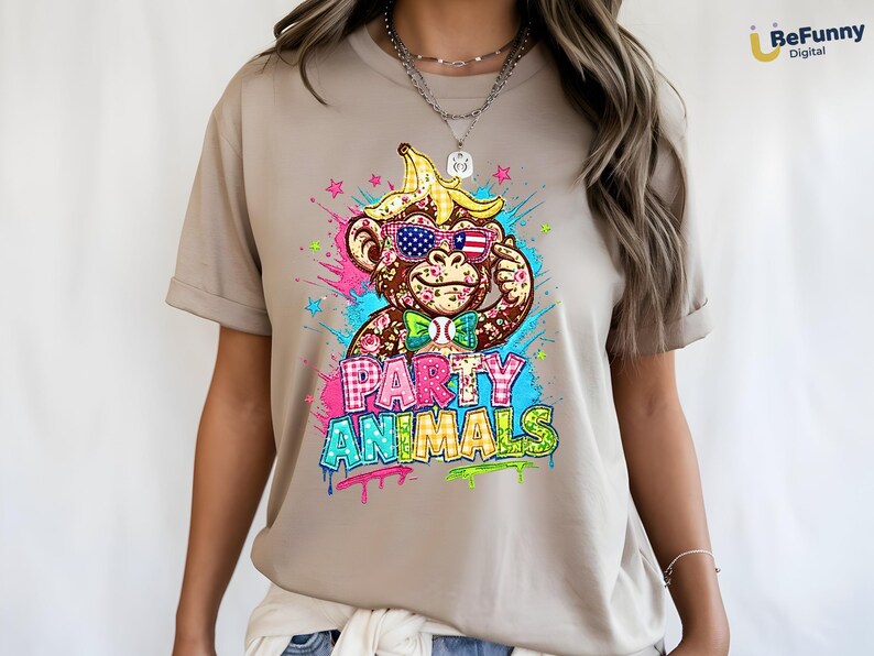 Puede incluir: Camiseta color beige con un gr&aacute;fico colorido de un mono con gafas de sol, un sombrero de c&aacute;scara de pl&aacute;tano y una pajarita. El texto "PARTY ANIMALS" se muestra en una fuente de estilo graffiti con efectos de salpicaduras de pintura.