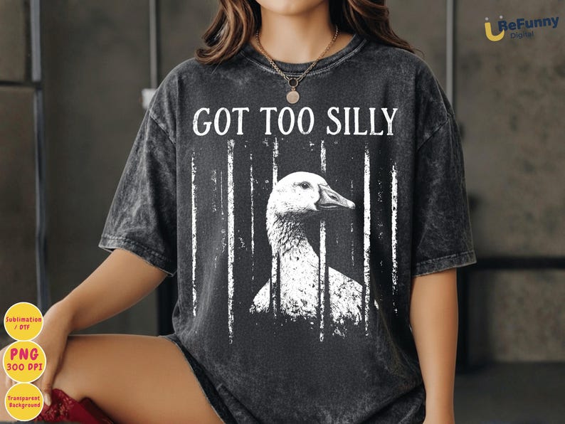 May include: Dark gray t-shirt with the text "GOT TOO SILLY" above a white graphic of a goose. The goose is behind white vertical lines. The shirt has a vintage, washed look.