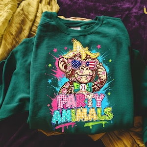 Puede incluir: Sudadera verde oscuro con un mono de dibujos animados con gafas de sol con un dise&ntilde;o de bandera estadounidense y un pl&aacute;tano en la cabeza. El texto "PARTY ANIMALS" se muestra en letras coloridas estilo grafiti.