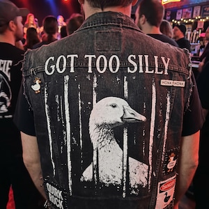 May include: A black denim vest with a large white graphic of a goose behind bars. The text "GOT TOO SILLY" is above the goose. Patches and pins with duck imagery and the words "HONK HONK" and "QUIRK ROCK" are also visible.