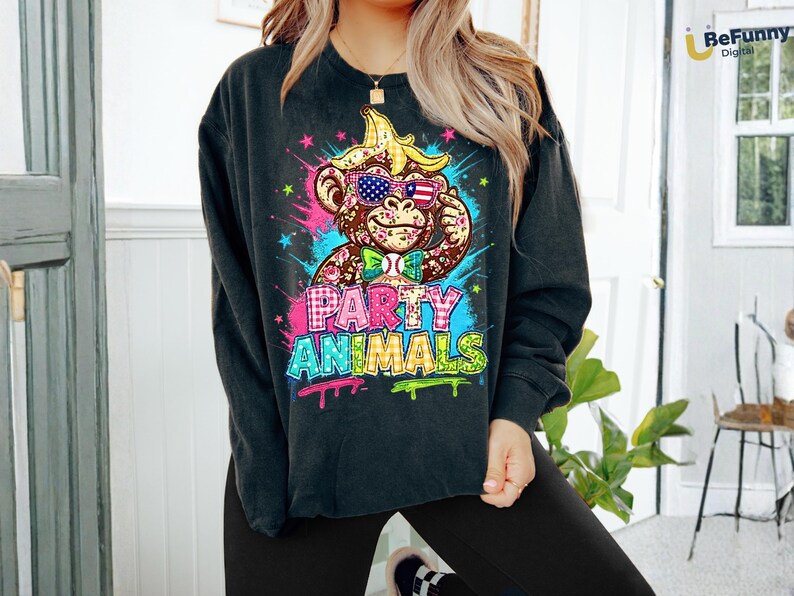 Puede incluir: Sudadera negra de cuello redondo con un gr&aacute;fico colorido de un mono con gafas de sol y pajarita. El mono tiene un pl&aacute;tano en la cabeza. Las palabras "PARTY ANIMALS" est&aacute;n escritas en estilo graffiti.