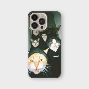 May include: A phone case featuring a group of cats wearing black hoodies. The cats have various fur patterns, including orange, black, and white. The text "Drysstudio" is visible on one of the hoodies. The case has a glossy finish.