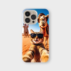 May include: A phone case featuring a selfie of a cat wearing sunglasses with a camel in the background. The cat is brown and tan with black sunglasses. The camel is brown and wearing a hat. The background is a desert scene.