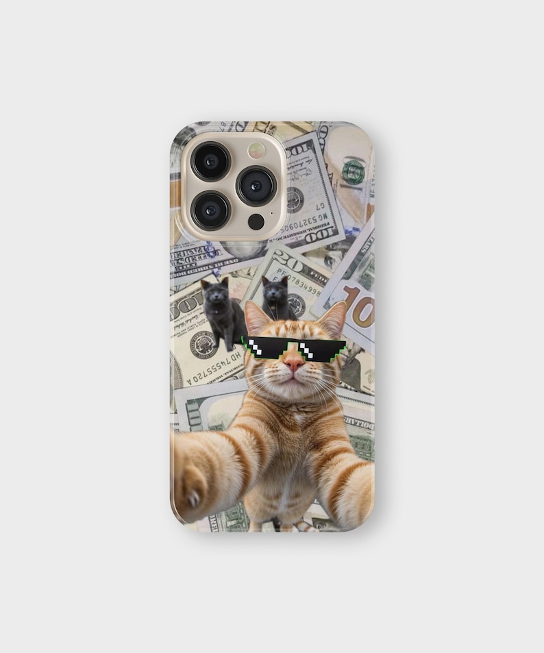 May include: A phone case featuring a selfie of a ginger cat wearing pixelated sunglasses, with two black kittens and a background of US hundred-dollar bills. The case has a glossy finish and a camera cutout.