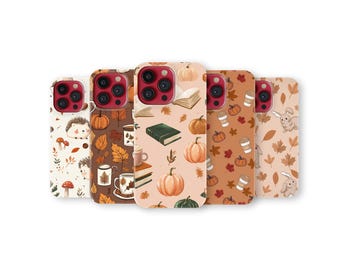 May include: A collection of five phone cases with autumn-themed designs. The cases feature illustrations of pumpkins, leaves, books, coffee cups, hedgehogs, and rabbits in warm, earthy tones. Each case has a different pattern.