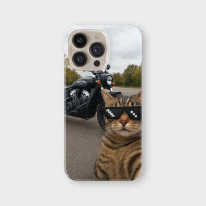 May include: A phone case featuring a tabby cat wearing pixelated sunglasses, with a black motorcycle in the background. The motorcycle has the word "INDIAN" on the side. The case is white with a camera cutout.