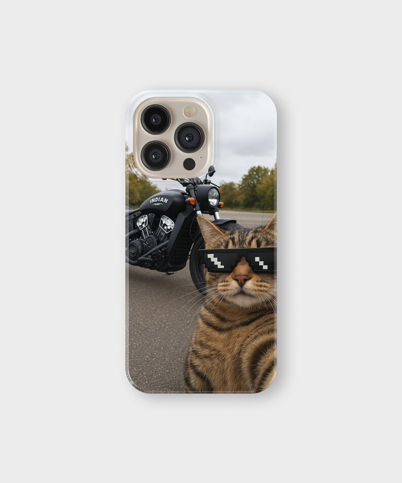 May include: A phone case featuring a tabby cat wearing pixelated sunglasses, with a black motorcycle in the background. The motorcycle has the word "INDIAN" on the side. The case is white with a camera cutout.