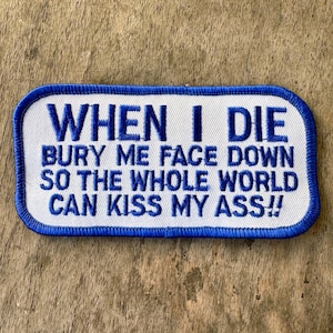 May include: A rectangular patch with a white background and a blue border. The patch features the text "WHEN I DIE BURY ME FACE DOWN SO THE WHOLE WORLD CAN KISS MY ASS!!" in blue capital letters.