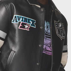 May include: Black leather jacket with white collar and accents. Features the "AVIREX" and "Starter" logos, along with an NFL emblem. The jacket has a snap-button closure and a design on the inner shirt that says "BOW" and "OBEY ARE".