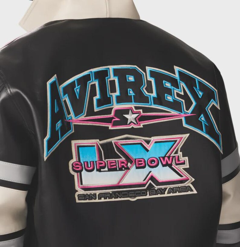 May include: Black and white leather jacket with the word "AVIREX" in blue and pink lettering across the back. Below the word "AVIREX" is a star and the words "SUPER BOWL LX" and "SAN FRANCISCO BAY AREA". The jacket has gray and white stripes on the sleeves.
