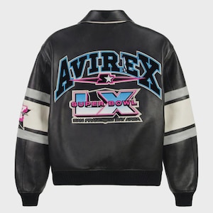 May include: Black leather bomber jacket with the word "AVIREX" in blue and pink lettering across the back. The jacket features the text "SUPER BOWL LX SAN FRANCISCO BAY AREA" in a graphic design. White and gray stripes adorn the sleeves.