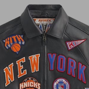 May include: Black leather jacket with "NEW YORK" and "KITH" patches in orange, blue, and white. Features a basketball graphic and the "AVIREX" logo. A stylish jacket for sports fans.