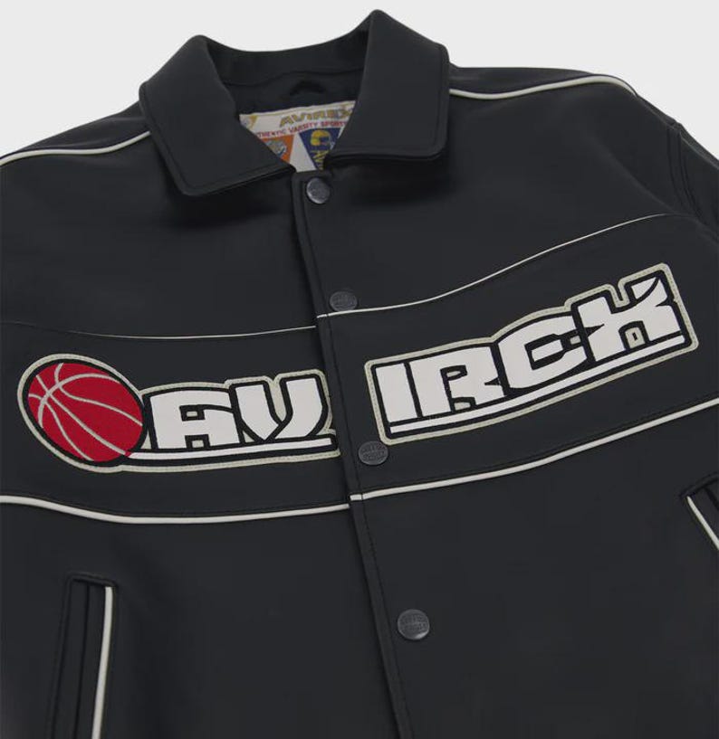 Puede incluir: Una chaqueta varsity negra con cuello blanco, cierre de botones a presi&oacute;n y detalles de ribetes blancos. El pecho muestra un gr&aacute;fico de baloncesto rojo y el texto bordado en blanco AVIRCK. La etiqueta interior dice AVIRCK AUTHENTIC VARSITY SPORTS.