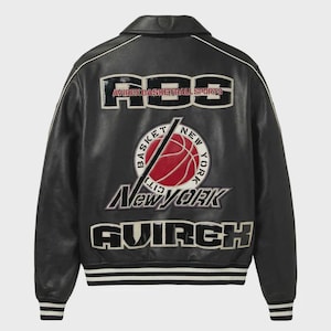 Puede incluir: Una chaqueta universitaria de cuero negro con parches bordados en blanco y rojo en la espalda. El dise&ntilde;o incluye el texto ABS, AVIREX BASKETBALL SPORTS, NEW YORK y AVIREX, junto con un gr&aacute;fico central de un bal&oacute;n de baloncesto rojo y una l&iacute;nea diagonal.