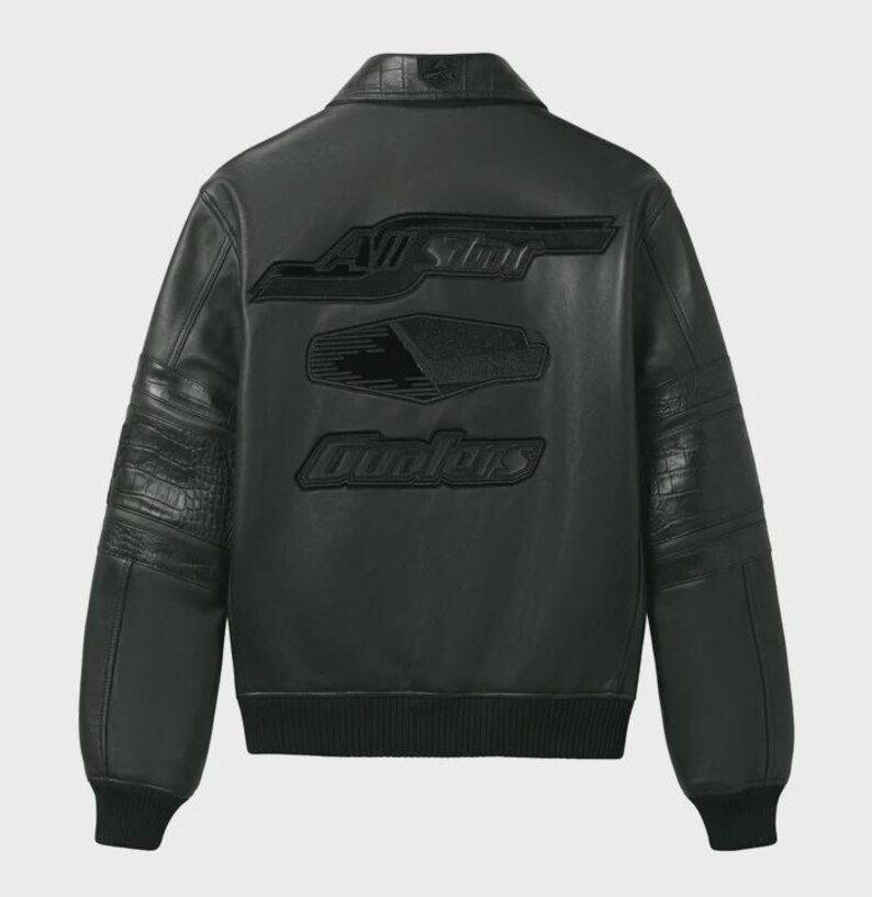 K&ouml;nnte beinhalten: Schwarze Lederjacke mit den Worten "ALL STAR" und "OUTLAWS" auf dem R&uuml;cken. Die Jacke hat einen gerippten Kragen und B&uuml;ndchen, mit einem strukturierten Muster auf den &Auml;rmeln.