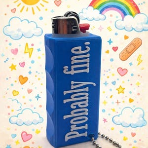 Puede incluir: Una funda azul para encendedor con la frase "Probably fine." en blanco. La funda tiene un agarre texturizado y una cadena plateada con un llavero. El fondo presenta un sol de dibujos animados, un arcoíris, nubes, corazones y estrellas.