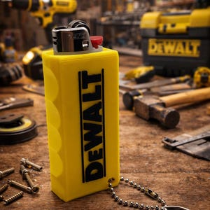 May include: A yellow lighter with the word "DEWALT" in black lettering. The lighter has a silver top with a red button and is attached to a keychain. The background includes tools and a toolbox.