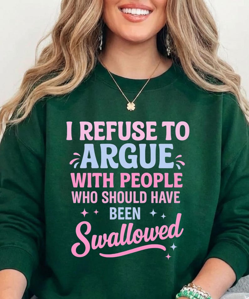 K&ouml;nnte beinhalten: Dunkelgr&uuml;nes Sweatshirt mit dem Text "I REFUSE TO ARGUE WITH PEOPLE WHO SHOULD HAVE BEEN SWALLOWED" in Rosa und Hellblau. Das Sweatshirt hat einen Rundhalsausschnitt und lange &Auml;rmel.