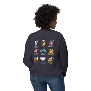 May include: A navy blue sweatshirt with various colorful graphics and text. The graphics include a raised fist, a rainbow flag, and illustrations with text such as "Black Lives Matter", "Love is Love", and "Feminism is for Everyone".