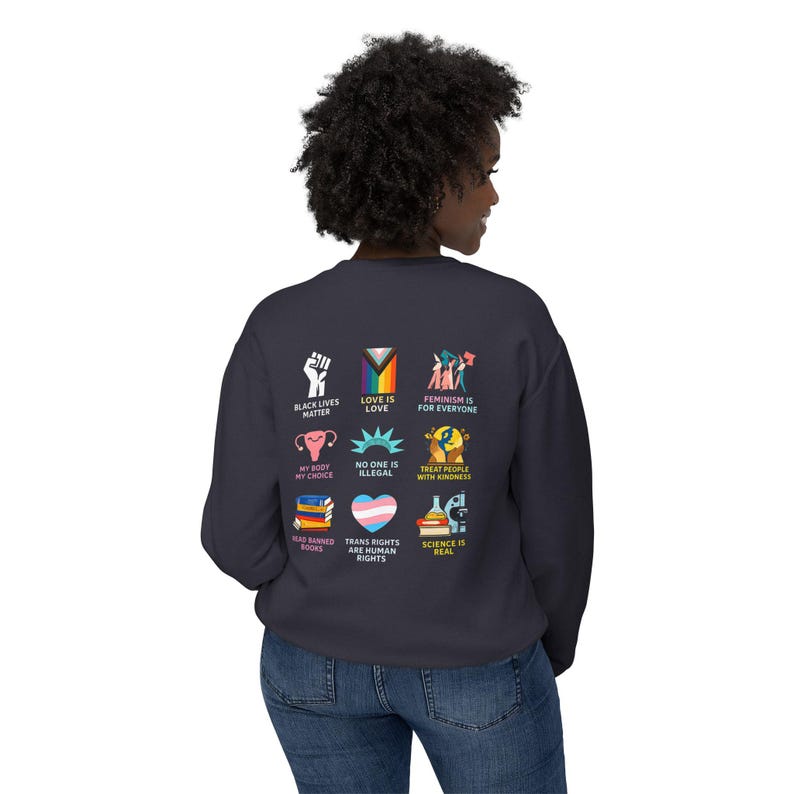 May include: A navy blue sweatshirt with various colorful graphics and text. The graphics include a raised fist, a rainbow flag, and illustrations with text such as "Black Lives Matter", "Love is Love", and "Feminism is for Everyone".