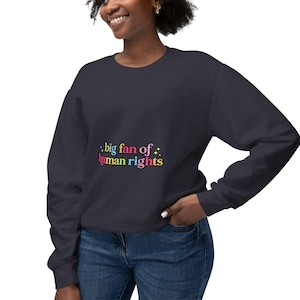 May include: Navy blue sweatshirt with the text "big fan of human rights" in colorful lettering. The sweatshirt is a solid color and has long sleeves. The text is in a playful font with a star graphic.