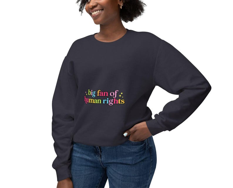 May include: Navy blue sweatshirt with the text "big fan of human rights" in colorful lettering. The sweatshirt is a solid color and has long sleeves. The text is in a playful font with a star graphic.