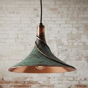 May include: A copper and verdigris pendant light fixture. The light has a conical shade with a copper interior and a green exterior. A copper spiral detail wraps around the top of the fixture. The light hangs from a black cord.