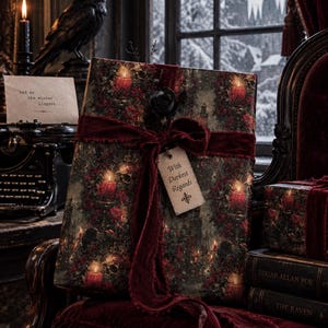 May include: A rectangular gift wrapped in dark paper featuring a pattern of red candles and greenery, tied with a deep red velvet ribbon. A black rose is attached to the center, and a cream-colored tag hangs from the bow with the text With Darkest Regards.