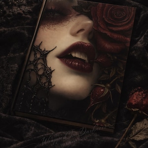 May include: A book cover featuring a woman's face with dark red lipstick and a rose. The title "Wrapped In Darkness" is visible. The image has a gothic, romantic theme, with dark colors and dramatic lighting.