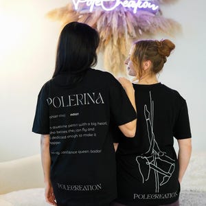 Könnte beinhalten: Zwei Personen tragen schwarze T-Shirts. Eines zeigt das Wort "POLERINA" mit einer Definition und "POLECREATION" darunter. Das andere hat eine Pole-Dance-Grafik und "POLECREATION". Ein Neon-Schild zeigt "PoleCreation".