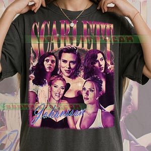 May include: Dark gray t-shirt featuring a graphic of Scarlett Johansson with the text "Scarlett Johansson" in a vintage style. The design includes multiple images of the actress in various poses, with a retro color scheme.