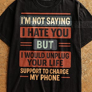 Puede incluir: Camiseta negra con un aspecto vintage desgastado. La camiseta presenta el texto "I'M NOT SAYING I HATE YOU BUT I WOULD UNPLUG YOUR LIFE SUPPORT TO CHARGE MY PHONE" en un diseño en capas con texto naranja, azul y blanco.