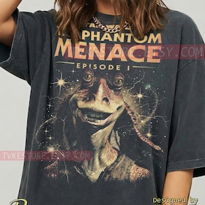 May include: Dark gray t-shirt featuring a graphic of Jar Jar Binks from Star Wars: Episode I - The Phantom Menace. The design includes the movie title and a space-themed background. The shirt is a vintage style.