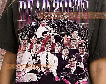 May include: Dark gray t-shirt featuring a graphic of the film "Dead Poets Society." The design includes the film's title in a purple and white font, along with a group of men. The shirt has a vintage, distressed look.