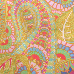 Op de afbeelding: Een paisley-patroon stof met een geel, roze, blauw en groen kleurenschema. De stof heeft een paisley-ontwerp met een herhalend patroon van bladeren en bloemen.