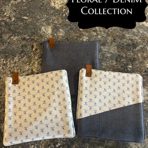 May include: Three square fabric pot holders with a brown leather tab and metal rivet. One is solid dark blue, one features a small blue floral pattern on a white background, and one combines both fabrics. Text at the top reads Floral / Denim Collection.