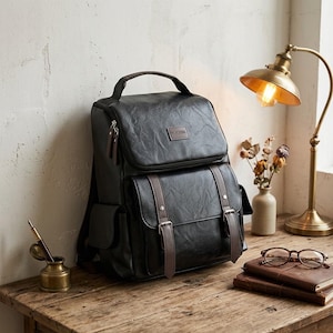 Può includere: Uno zaino nero con finitura testurizzata, dotato di manico superiore, tasca frontale con patta e due cinghie verticali marroni, e una targhetta rettangolare con la scritta HUIERNA. La borsa presenta tasche laterali e tiretti della cerniera in metallo argentato.