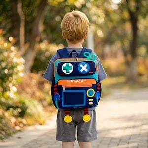 Peut inclure: Un sac à dos bleu marine et turquoise sur le thème d'un robot, avec des accents orange et jaunes. Le sac à dos présente une croix et un X sur la poche supérieure, avec un écran et des boutons à l'avant. Il a des bretelles bleues et des pieds jaunes.