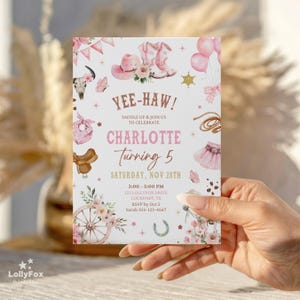 Puede incluir: Una invitaci&oacute;n rosa y blanca con tem&aacute;tica de vaquera. La invitaci&oacute;n presenta ilustraciones de botas de vaquero, un sombrero y una silla de montar. El texto incluye "Yee-Haw!" y "Charlotte Turning 5". Tambi&eacute;n se incluyen los detalles del evento.