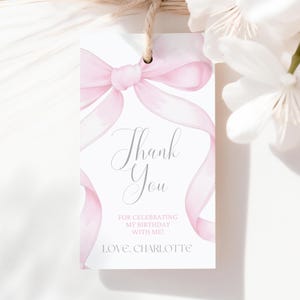May include: A white gift tag featuring a pink watercolour bow and ribbon design. The tag says "Thank You" in elegant script, with additional text below. A natural twine string is attached at the top.