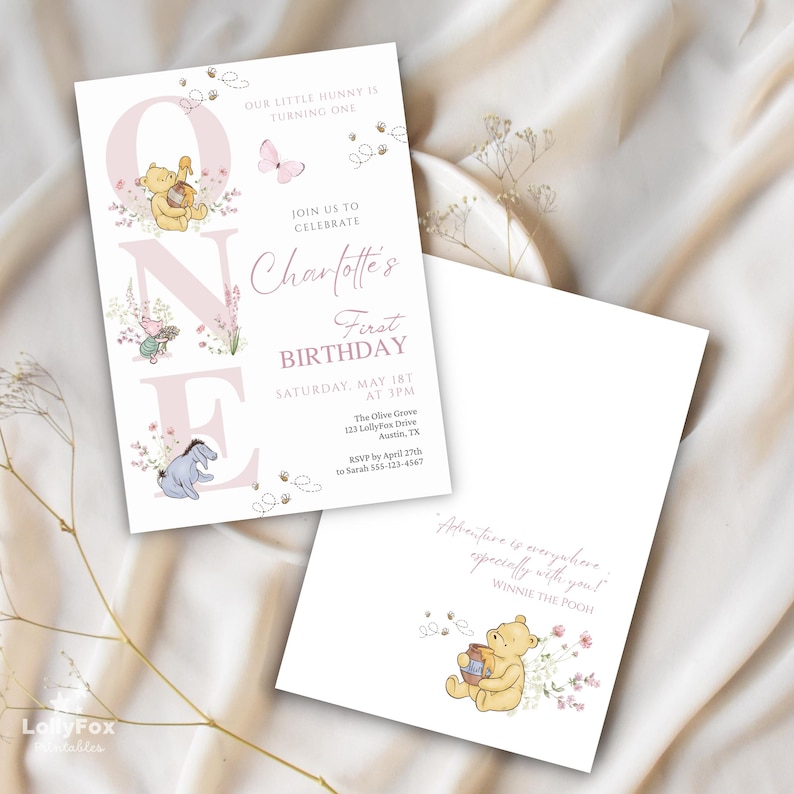 May include: Two white invitations with Winnie the Pooh theme. The front invitation has the text "Charlotte's First Birthday" with illustrations of Winnie the Pooh, Piglet, and Eeyore. The back invitation has the text "Adventure is everywhere especially with you! Winnie the Pooh."