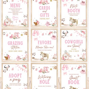 May include: Nine framed signs with a pink cowgirl theme. Each sign features text such as "Menu", "Cards and Gifts", and "Photo Booth", along with floral and cowboy-themed illustrations. The signs are arranged on a light wood surface.
