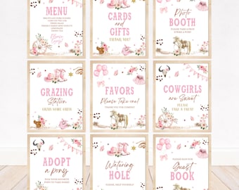 May include: Nine framed signs with a pink cowgirl theme. Each sign features text such as "Menu", "Cards and Gifts", and "Photo Booth", along with floral and cowboy-themed illustrations. The signs are arranged on a light wood surface.