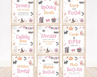 May include: A set of nine rectangular signs with light wooden frames, featuring pink and orange Halloween-themed text and illustrations including ghosts, pumpkins, bats, cats, and cauldrons on a white background with scattered confetti dots.