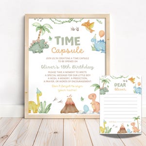Puede incluir: Una impresión enmarcada y una tarjeta a juego con un tema de dinosaurios. La impresión dice "Time Capsule" e invita a los invitados a escribir mensajes para el 18 cumpleaños de Oliver. La tarjeta está preimpresa con "Querido Oliver" y líneas para escribir.