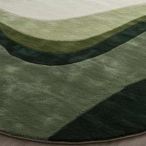 May include: A round rug with a wave-like design in shades of green. The rug features a soft, plush texture and a gradient of colors, from light green to dark green. The rug is approximately 60 inches in diameter.