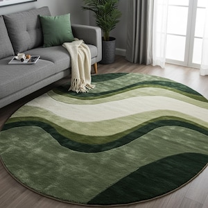 Puede incluir: Una alfombra redonda con un diseño ondulado en tonos verdes y blanco roto. El diseño de la alfombra presenta líneas fluidas, creando una sensación de movimiento. La alfombra está colocada sobre un suelo de madera, cerca de un sofá gris.