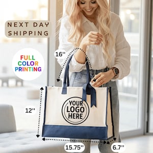 A smiling woman holding a large tote bag with a logo printed on it.